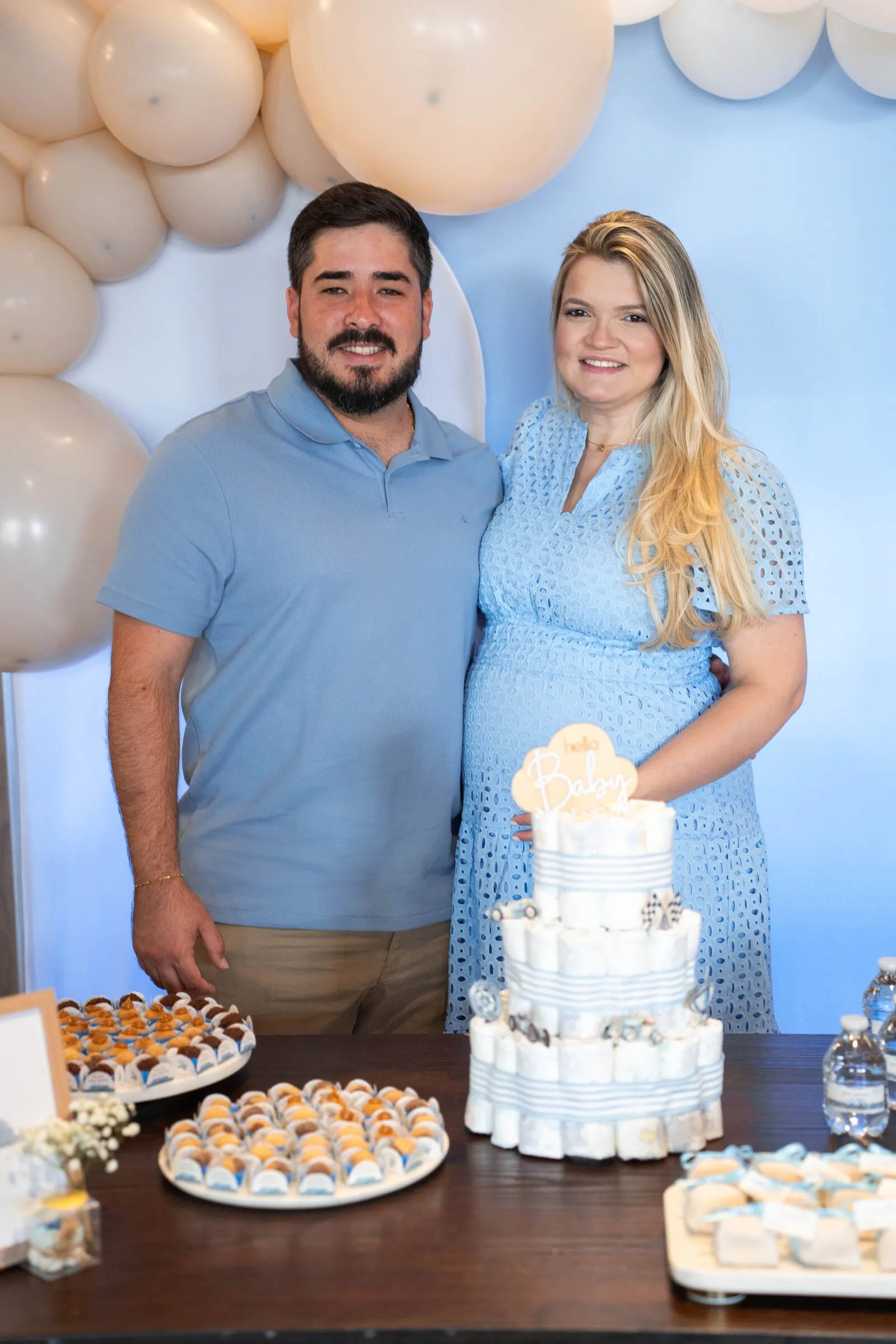 Expecting parents standing in front of a balloon arch at their baby shower
