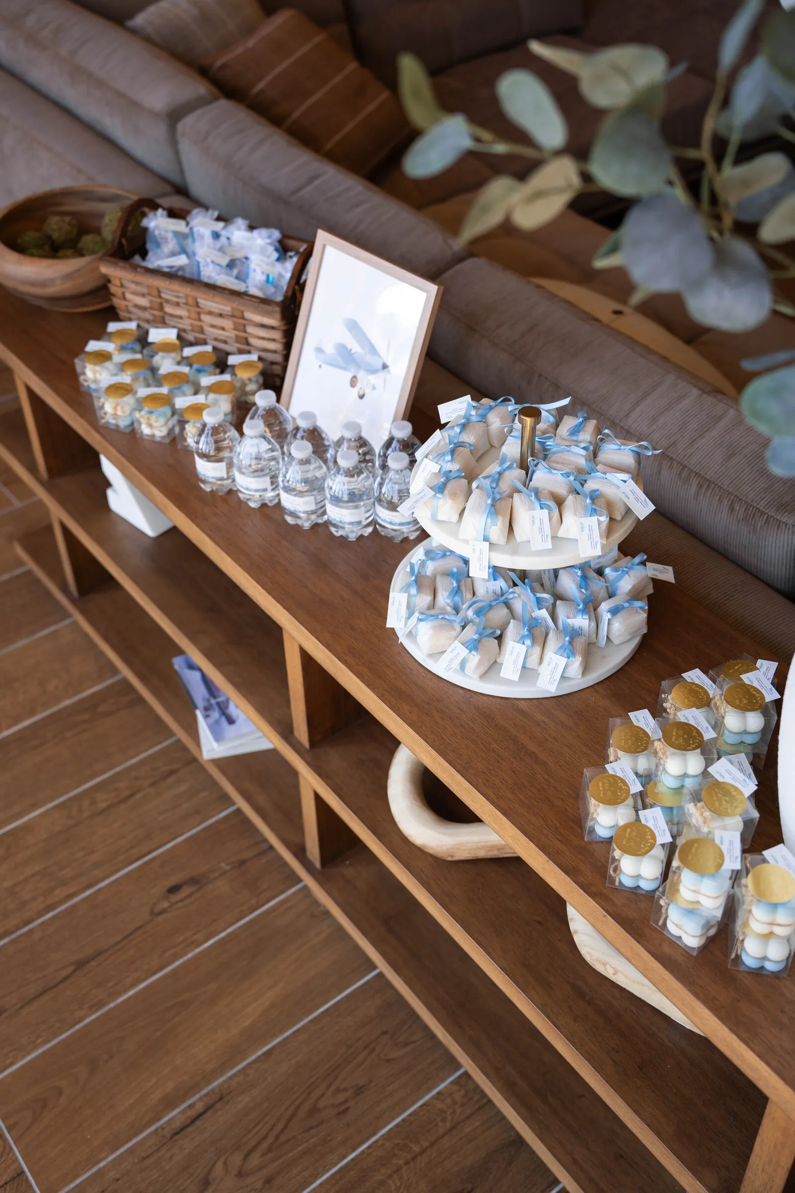 Ribbon-tied favors and treat boxes arranged on a console table at the baby shower