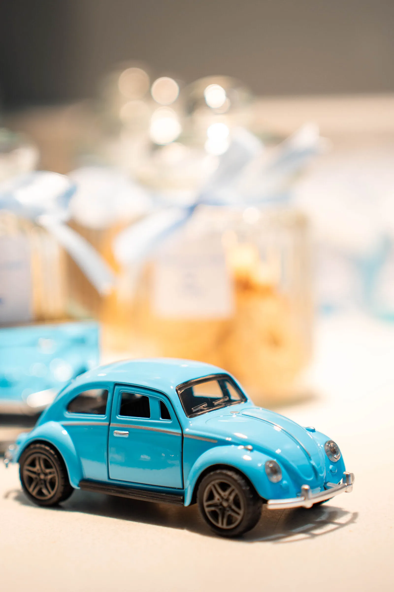 A miniature toy Volkswagen Beetle parked among the baby-shower favor jars