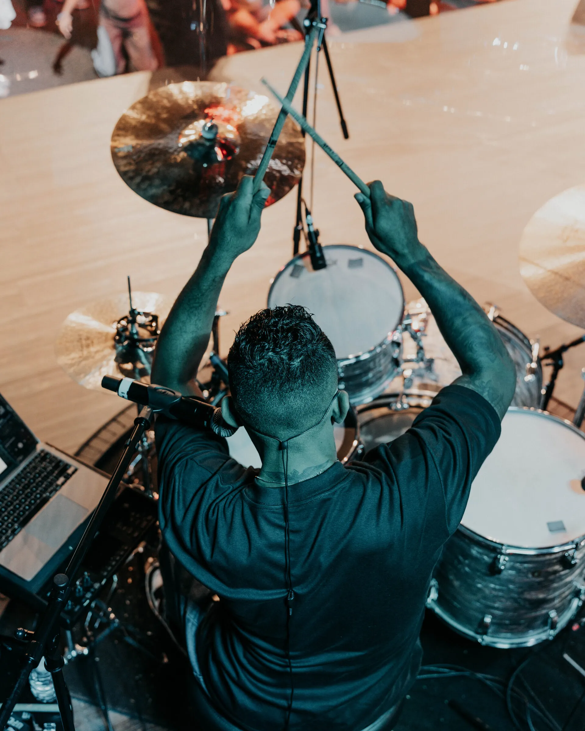 A drummer photographed from above, sticks raised over the cymbals