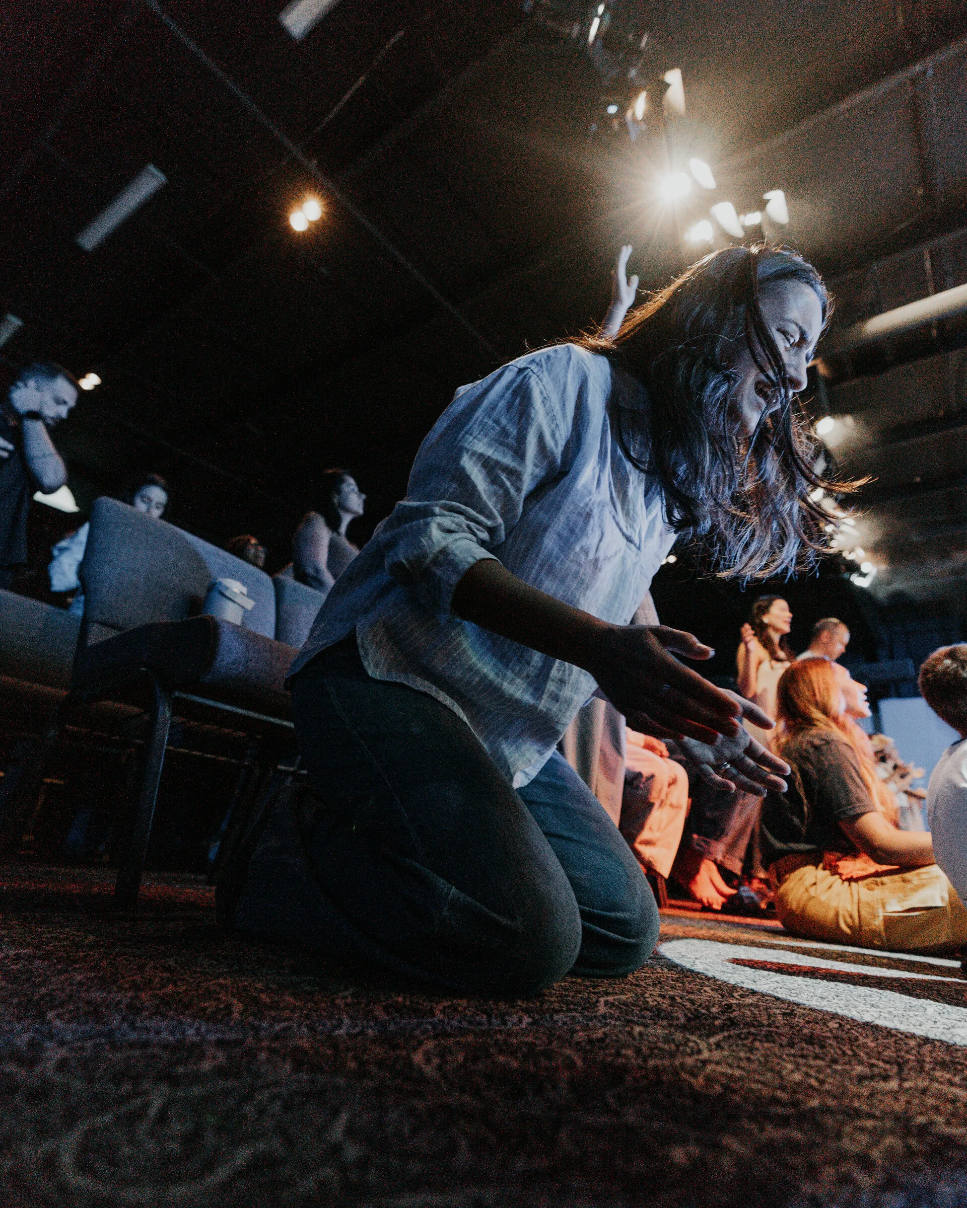 People kneeling on a rug at the front of the room in warm light
